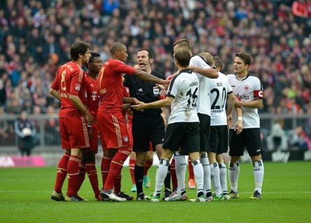Mass confrontation of players from FC Bayern and Eintracht Frankfurt discussing a decision with referee Marco Fritz