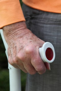 Elderly woman standing with a crutch in her hand