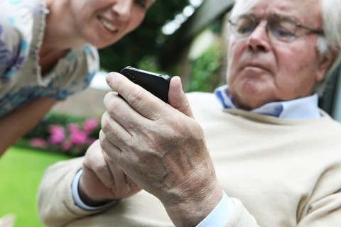 Young woman explaining to a senior citizen how to use a smartphone