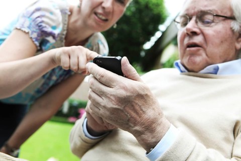Young woman explaining to a senior citizen how to use a smartphone