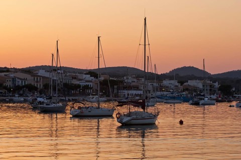 Sailing boats in a harbour at sunset