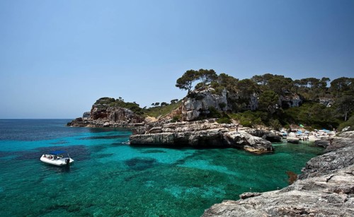 Boat in the rock-lined bay of Calo des Moro