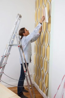 Young woman wallpapering a wall