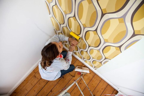Young woman wallpapering a wall