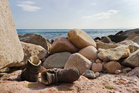 Hiking shoes lying on the beach of Mari Pintau