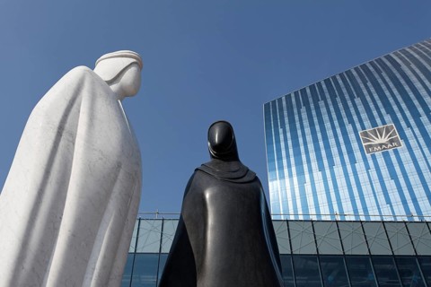 Sculpture of an Arab man and an Arab woman in front of the EMAAR building