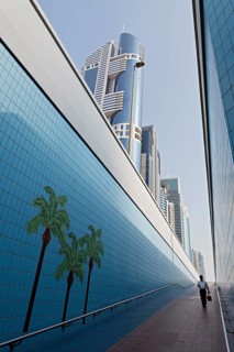 Single person walking through a pedestrian underpass with painted palm trees