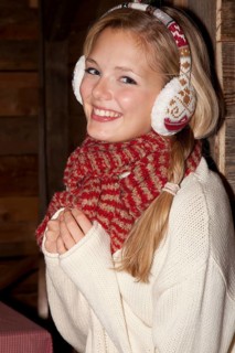 Smiling young woman wearing ear warmers and a scarf in a hiking hut