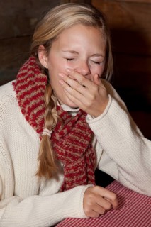 Young woman wearing a scarf sitting at the table of a hiking hut and yawning