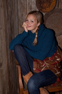 Smiling young woman with a blanket in a hiking hut
