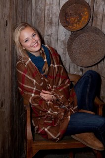 Smiling young woman wrapped in a blanket in a hiking hut