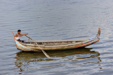 Man in a traditional rowing boat on the Taungthaman Lake