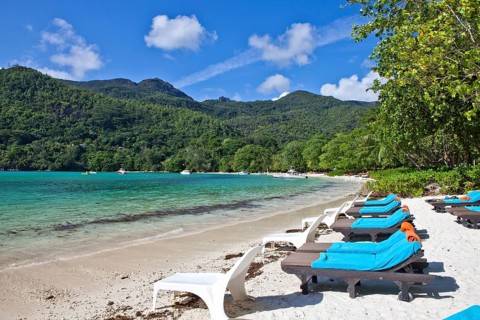 Sunloungers on the beach of the Ephelia Resort at Port Launay Marine National Park