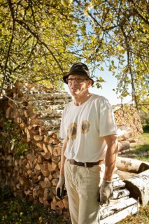 Man in the orchard in front of a wood pile