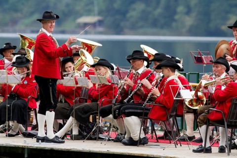 The Weissensee marching band in traditional costumes with conductor Johann Knaller performing on a raft at the Naturparkfest festival in Techendorf