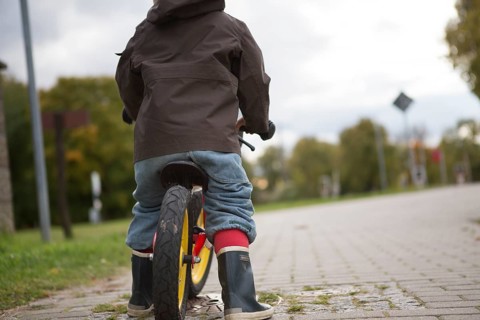 A young boy is practicing to ride a bicycle on a quiet street