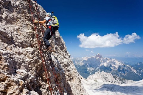 Mountaineer climbing the Via Ferrata Ivano Dibona climbing route to the summit of Monte Cristallo to the summit of Cristallino above Cortina