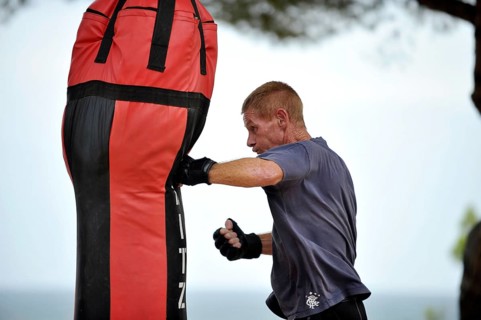 Man practicing punches on a punching bag in a park