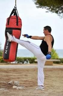 Man is kicking a sandbag during a training session