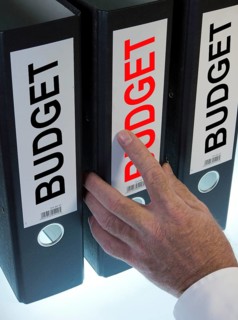 Hand reaching for a ring binder labelled 'BUDGET'