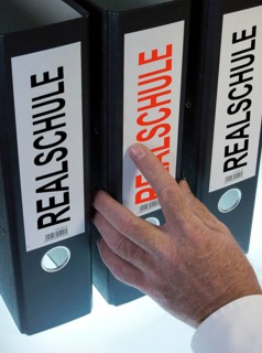Hand reaching for a file folder labeled 'Realschule'