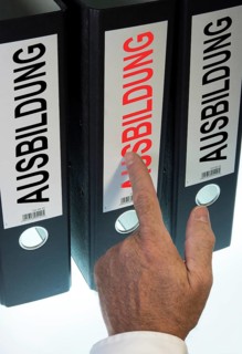 Hand pointing to a file folder labeled 'Ausbildung'
