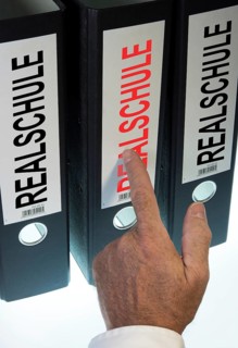 Hand pointing to a file folder labeled 'Realschule'