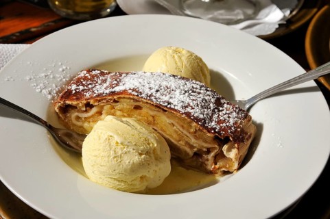 Apple strudel served with vanilla ice cream on a white plate