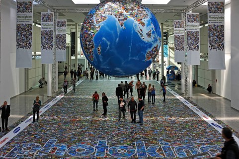 Installation depicting the global flood of images on a globe and on the floor in an exhibition hall