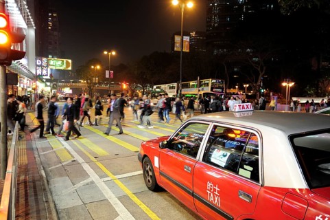A red taxi waiting at a zebra crossing on Chatham Road in the evening