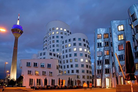 A building by American architect Frank O. Gehry and the Rheinturm tower at night
