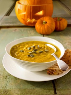 Pumpkin and bacon soup with a traditional Halloween pumpkin with a carved face