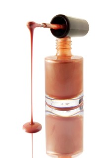 Nail varnish dripping from a nail varnish brush balanced on a nail varnish bottle