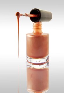 Pink nail varnish dripping from a nail varnish brush balanced on a nail varnish bottle