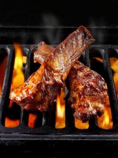 BBQ spare ribs being cooked over open flames