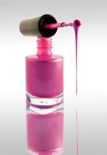 Pink nail varnish dripping from a nail varnish brush balanced on a nail varnish bottle