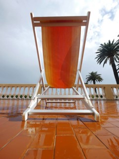 Deck chair on a porch under palm trees