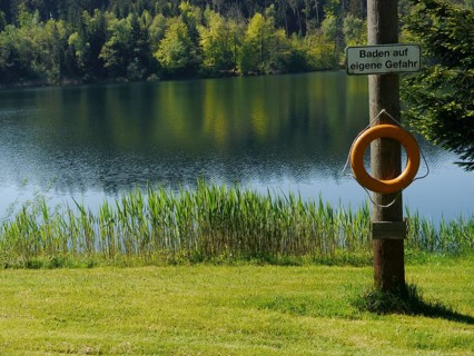 Lifebuoy and sign 'Baden auf eigene Gefahr'