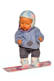 Baby doll with ski clothes on a snowboard