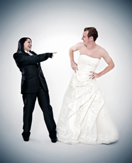 Bride wearing a suit laughing at a groom wearing a wedding dress