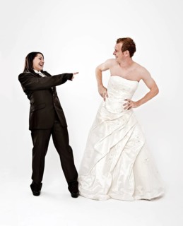 Bride wearing a suit laughing at a groom wearing a wedding dress