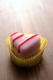 Pink heart-shaped petit four on a wooden surface