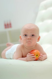 Baby lying on his stomach with an apple