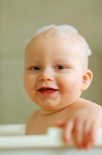 Baby in a bath with foam on his head