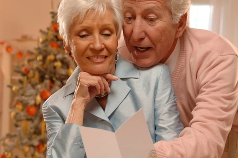 Mature couple reading Christmas cards in front of a Christmas tree