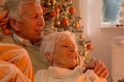 Mature couple in love sitting on a sofa in front of a Christmas tree