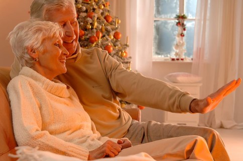 Mature couple in love sitting on a sofa in front of a Christmas tree