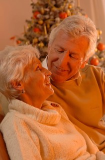 Mature couple in love sitting in front of a Christmas tree