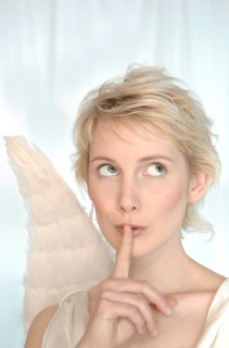 Blonde woman with angel wings making a silence gesture