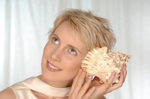 Young woman holding large shell to her ear